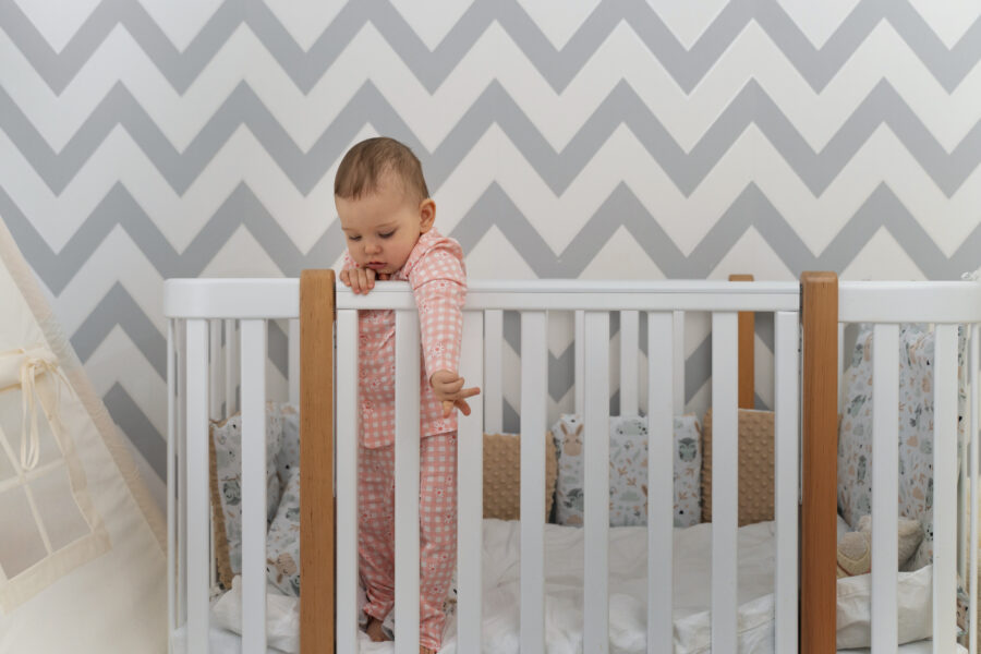 Baby enjoying standing within the cot