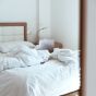 Bed with a white duvet and a laptop on it. 
