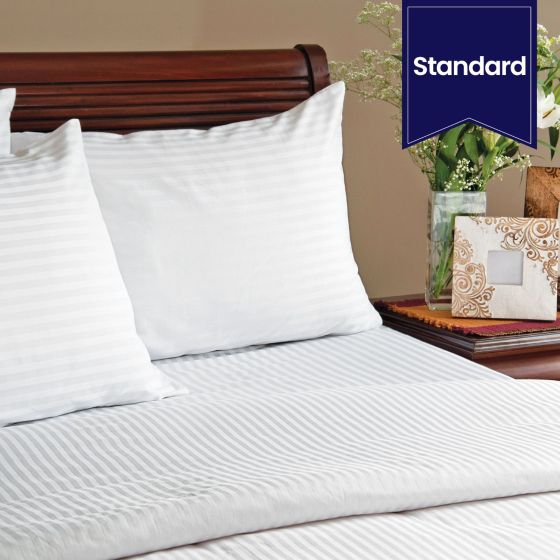 A bed with two pillows using Swiss Stripes.